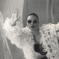 Editorial black and white portrait of a woman in White Angel sunglasses and ruffles.