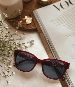 White Angel burgundy cat-eye sunglasses with floral temples and fashion magazine.