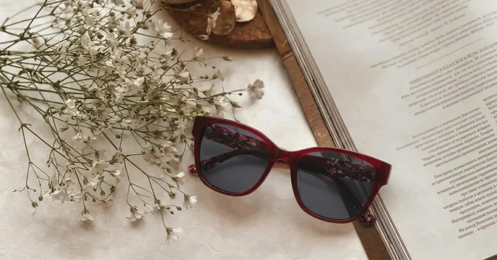 Elegant red eyewear frame next to book.