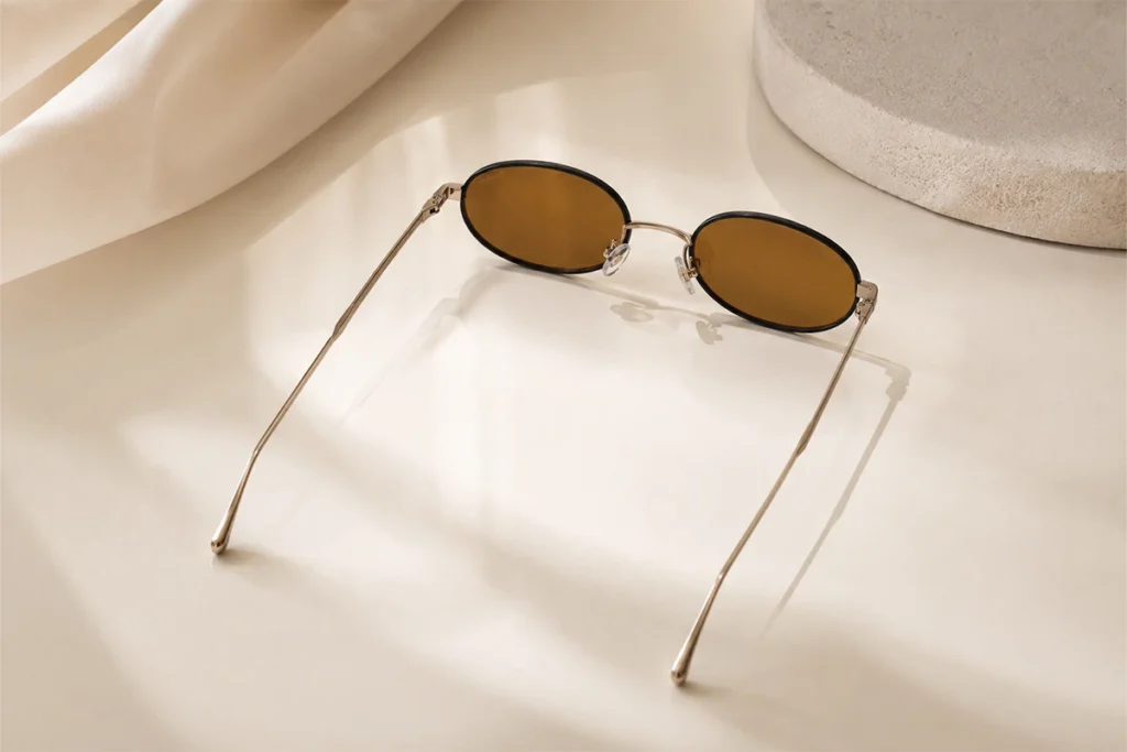 Brown oval sunglasses on cream surface, White Angel Eyewear